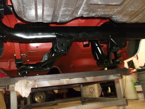 1967 Ford Mustang - The underside of a vehicle is shown, suspension components and a red painted chassis.