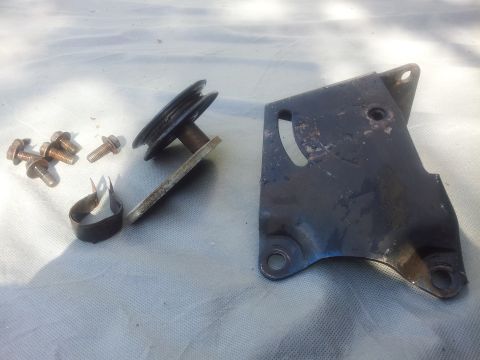 1976 Ford Ranchero - A collection of air conditioning system parts, including a bracket, pulley, and fasteners, are laid out on a cloth surface.