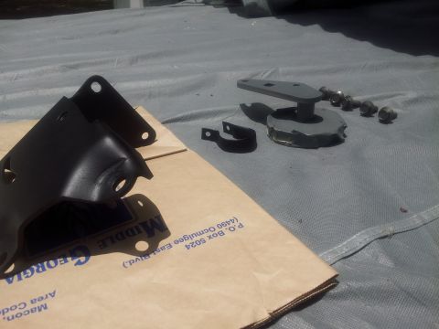1976 Ford Ranchero - Several automotive parts, including brackets and bolts, are arranged on a tarp next to a shipping box.