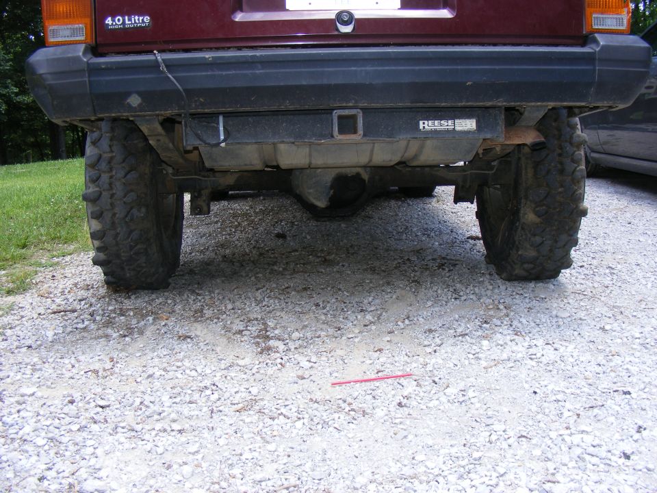 Maroon SUV rear axle with large tires and a Reese hitch receiver