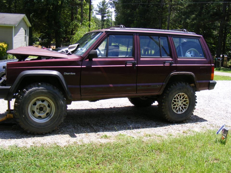 Maroon SUV side view, hood up. "Cherokee" text visible