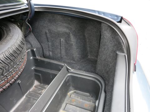 2001 Ford Crown Victoria - The trunk of a vehicle, showing the spare tire and a plastic storage compartment.