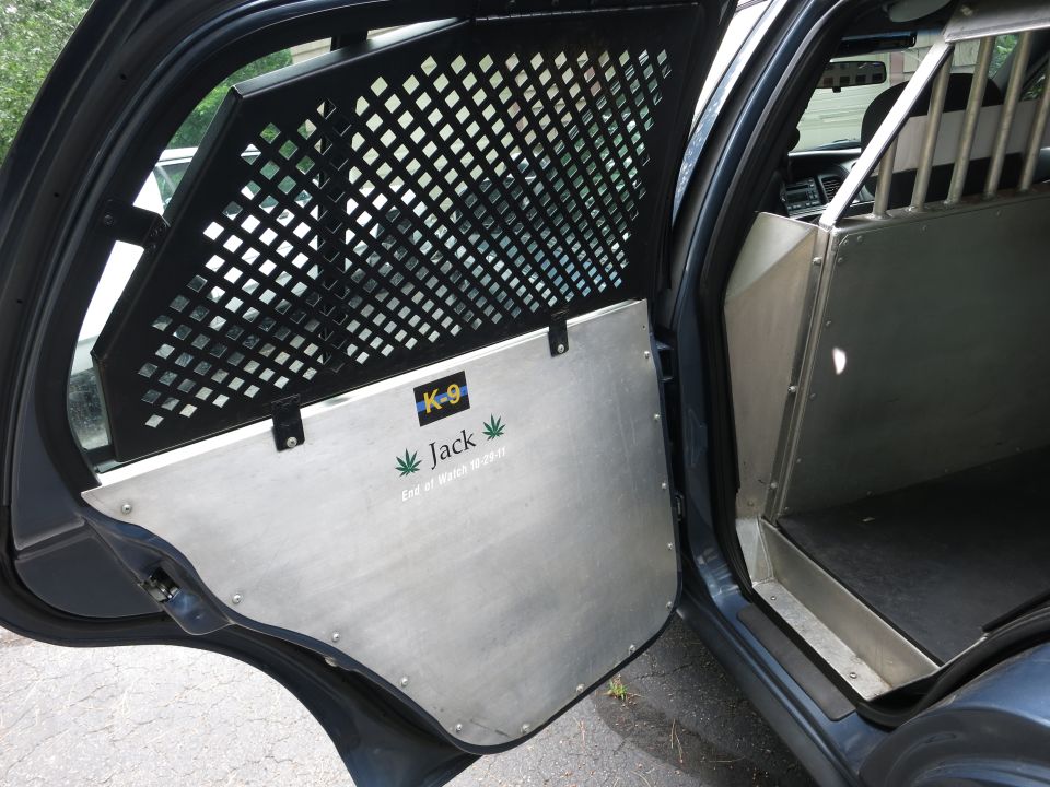 Interior of a police vehicle showing a K-9 partition and door panel with 'K-9 Jack' text