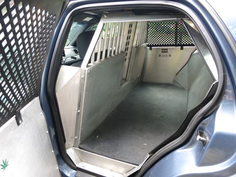 2001 Ford Crown Victoria - The rear interior of a modified vehicle, equipped with a K-9 unit cage and partition, is shown.