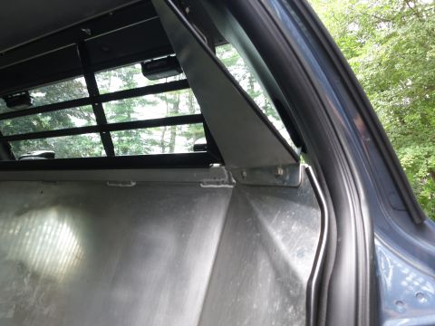 2001 Ford Crown Victoria - The interior of a vehicle shows a custom metal cargo area with security bars on the rear window.