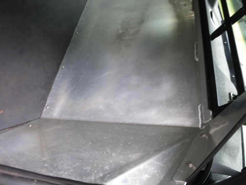 Interior view of a vehicle's cargo area showing metal flooring and black trim