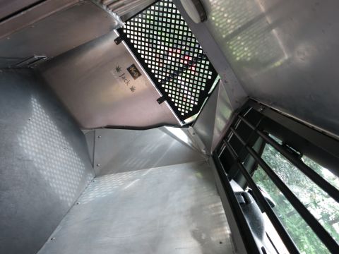 2001 Ford Crown Victoria - The interior of a vehicle's cargo area, possibly a K-9 unit, with metal walls and a barred window.