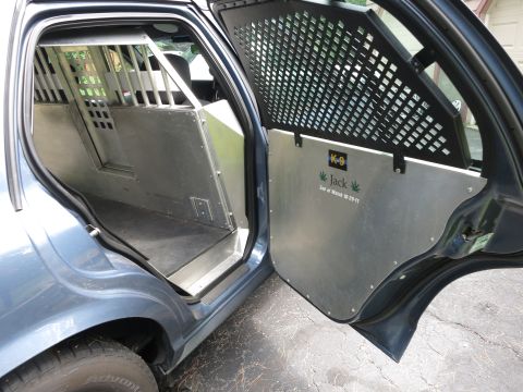 2001 Ford Crown Victoria - The interior of a police vehicle is shown, K-9 unit modifications including a cage and metal door panel with 'Jack' and 'End of Watch' text.
