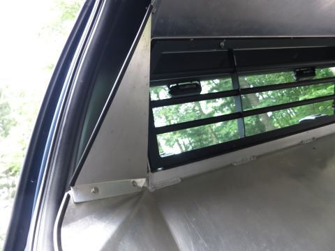 2001 Ford Crown Victoria - Close-up view of the interior of a vehicle, focusing on a window with blinds and surrounding metalwork.