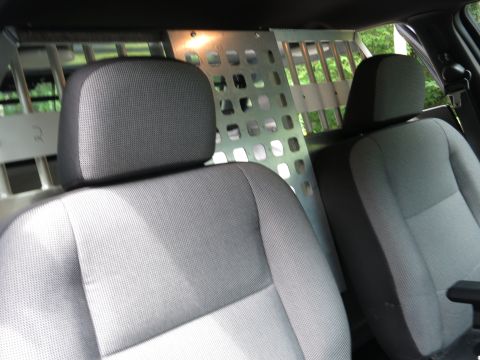 2001 Ford Crown Victoria - The interior of a vehicle shows front seats and a metal cage partition separating the front from the rear.