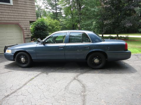 2001 Ford Crown Victoria - Side view of a blue 2001 Ford Crown Victoria parked in front of a garage.
