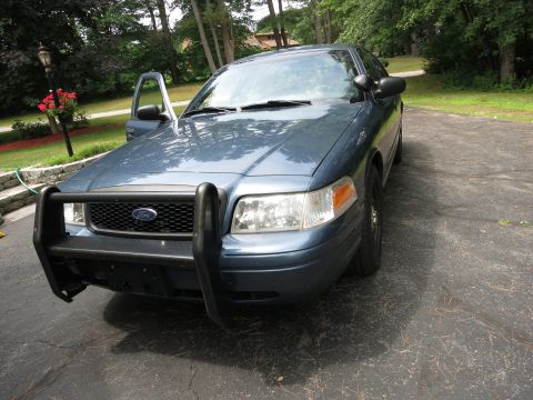 2001 Ford Crown Victoria - A blue Ford Crown Victoria Police Interceptor sits on a paved driveway with its driver's door ajar.