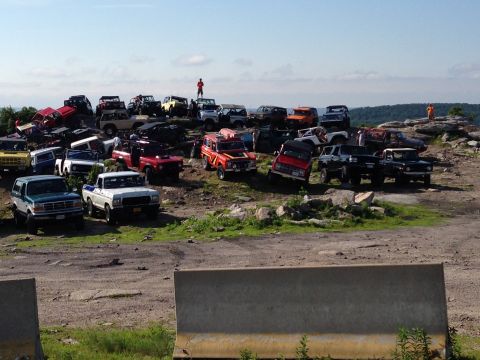 1988 Ford Bronco - A large group of off-road vehicles are gathered on a hill, with a few people visible.