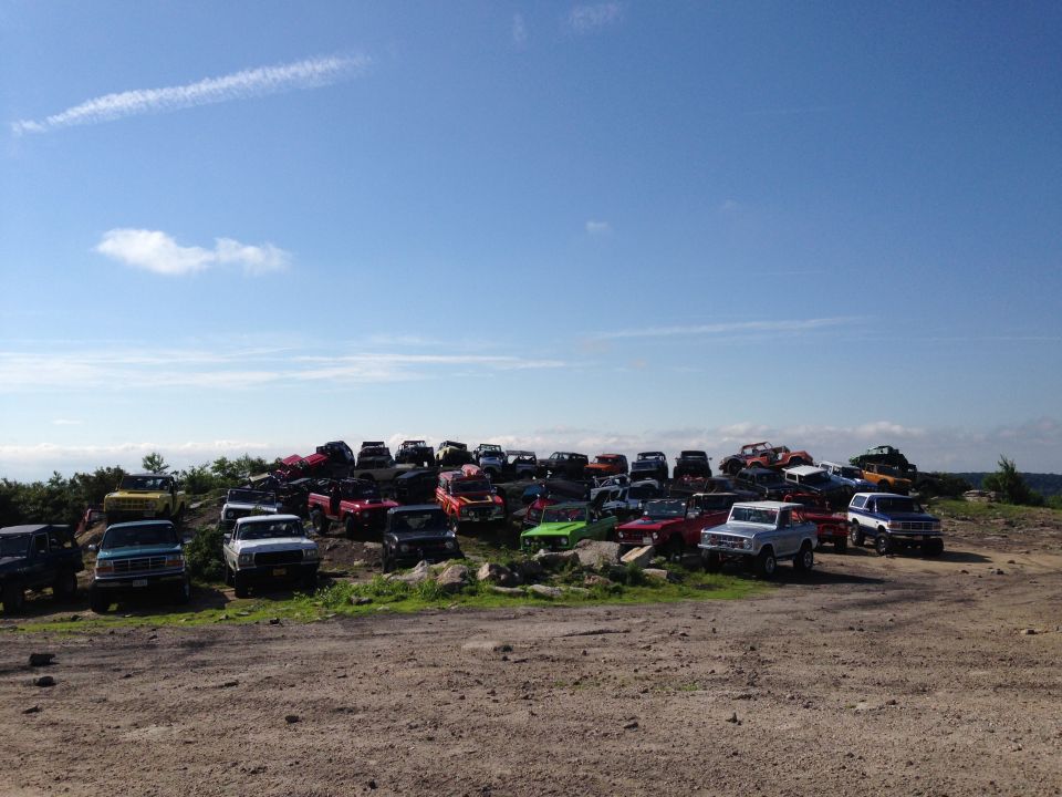 Junkyard filled with numerous trucks and SUVs under a blue sky
