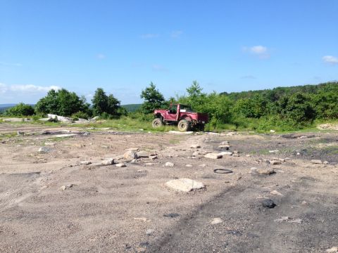 1988 Ford Bronco - A red pickup truck sits on a rocky hill under a clear blue sky.