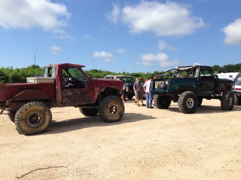 1988 Ford Bronco - Several heavily modified trucks are gathered outdoors on a sunny day.