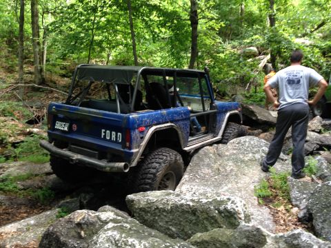 1988 Ford Bronco - A blue 1988 Ford Bronco navigates a rocky trail, its off-road capabilities.