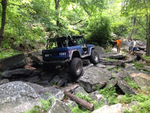 1988 Ford Bronco - Ford Bronco tackling a challenging rocky off-road course with spectators watching.