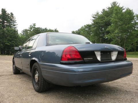 2001 Ford Crown Victoria - Rear view of a blue 2001 Ford Crown Victoria parked outdoors on a gravel surface.
