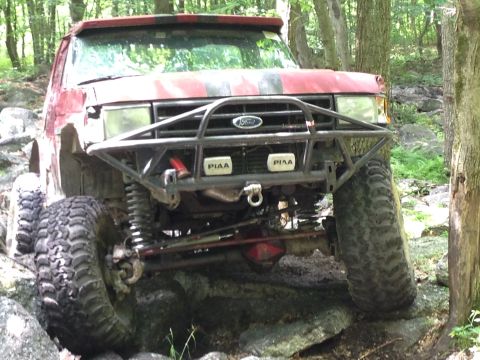 1988 Ford Bronco - This modified SUV navigates a challenging rocky path in a wooded area.