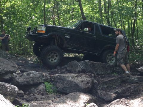 1988 Ford Bronco - A black Ford Bronco navigates a rocky trail in a wooded area.