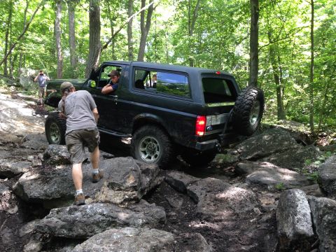 1988 Ford Bronco - Ford Bronco tackling a challenging off-road course in a wooded area.