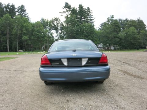 2001 Ford Crown Victoria - Rear view of a blue 2001 Ford Crown Victoria parked outdoors on a gravel surface.
