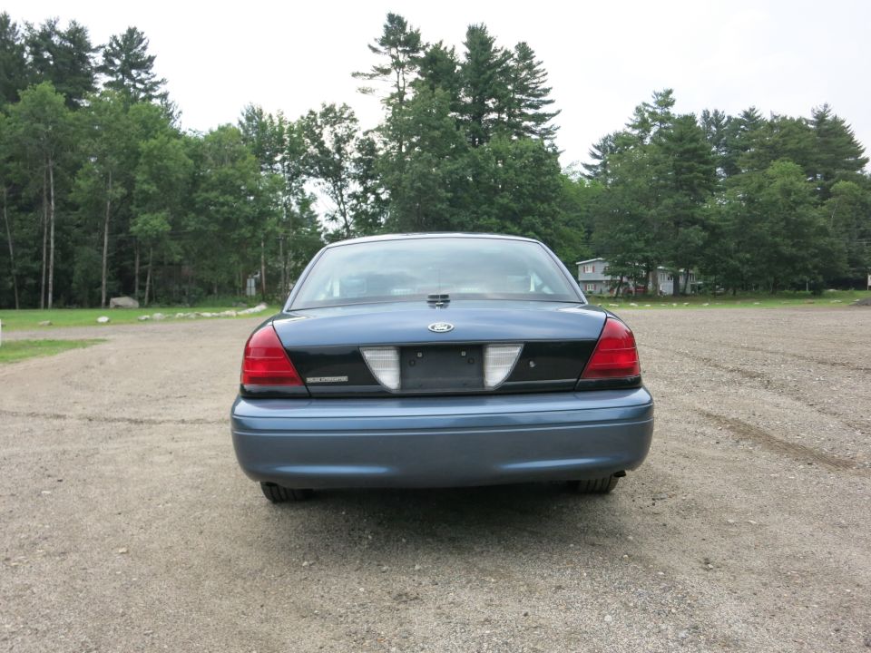 Blue 2001 Ford Crown Victoria rear view, parked on gravel lot