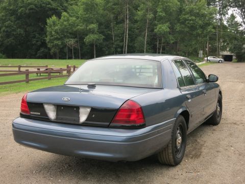 2001 Ford Crown Victoria - The rear quarter panel and taillight assembly of a blue Ford Crown Victoria are visible.