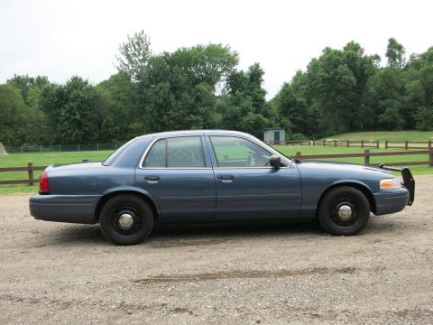 2001 Ford Crown Victoria - Side profile of a blue Ford Crown Victoria Police Interceptor, showing its distinctive body style and push bumper.