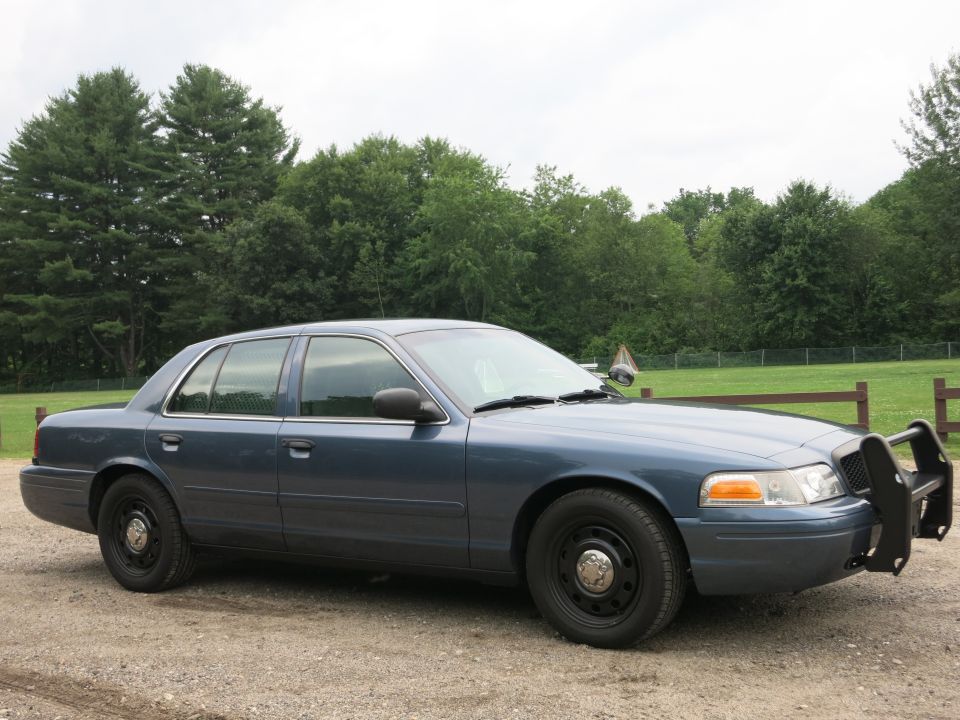 Blue 2001 Ford Crown Victoria police car with push bumper, side view