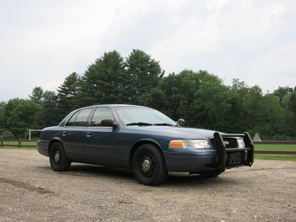2001 Ford Crown Victoria police car with push bumper parked on gravel