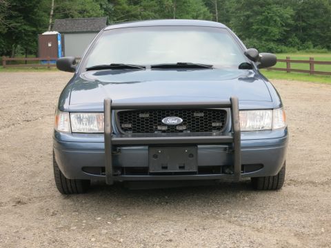 2001 Ford Crown Victoria - A blue 2001 Ford Crown Victoria is parked outside on a gravel lot, facing the camera.