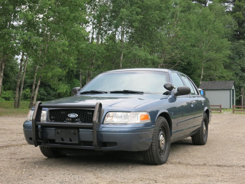 Blue 2001 Ford Crown Victoria police car with push bumper, front 3/4 view
