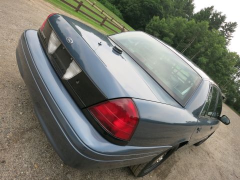 2001 Ford Crown Victoria - Rear view of a blue 2001 Ford Crown Victoria sedan on a gravel surface.