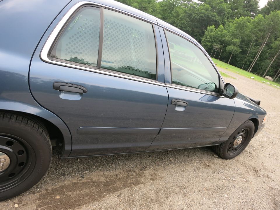 Side view of blue 2001 Ford Crown Victoria police car with cage windows