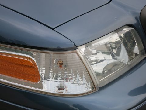2001 Ford Crown Victoria - Close-up of the front corner of a blue 2001 Ford Crown Victoria, highlighting the headlight and turn signal.