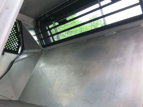 2001 Ford Crown Victoria - View from inside a vehicle's compartment, looking towards a barred window and metal interior panels.