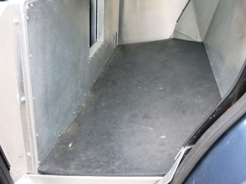 2001 Ford Crown Victoria - The interior cargo area of a vehicle shows metal walls and a rubber floor mat.