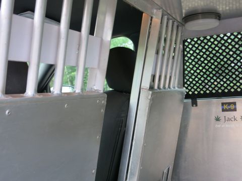 2001 Ford Crown Victoria - The interior of a vehicle is shown with metal bars and a K-9 decal on the wall.
