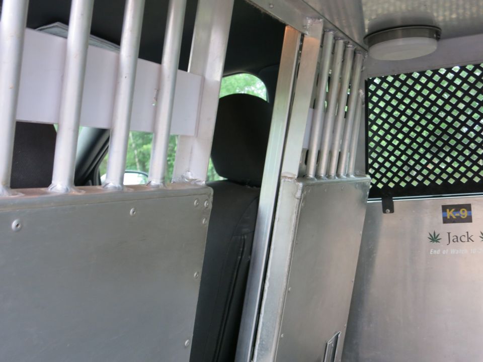 Interior of a vehicle with metal bars, a K-9 decal, and a seat