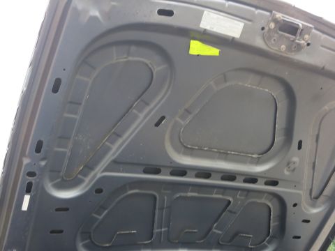2001 Ford Crown Victoria - The underside of a car's hood, showing structural bracing and two stickers, one yellow and one white with text.