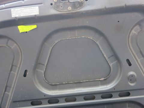 2001 Ford Crown Victoria - The underside of a car hood shows a white label with text and a bright yellow sticker.