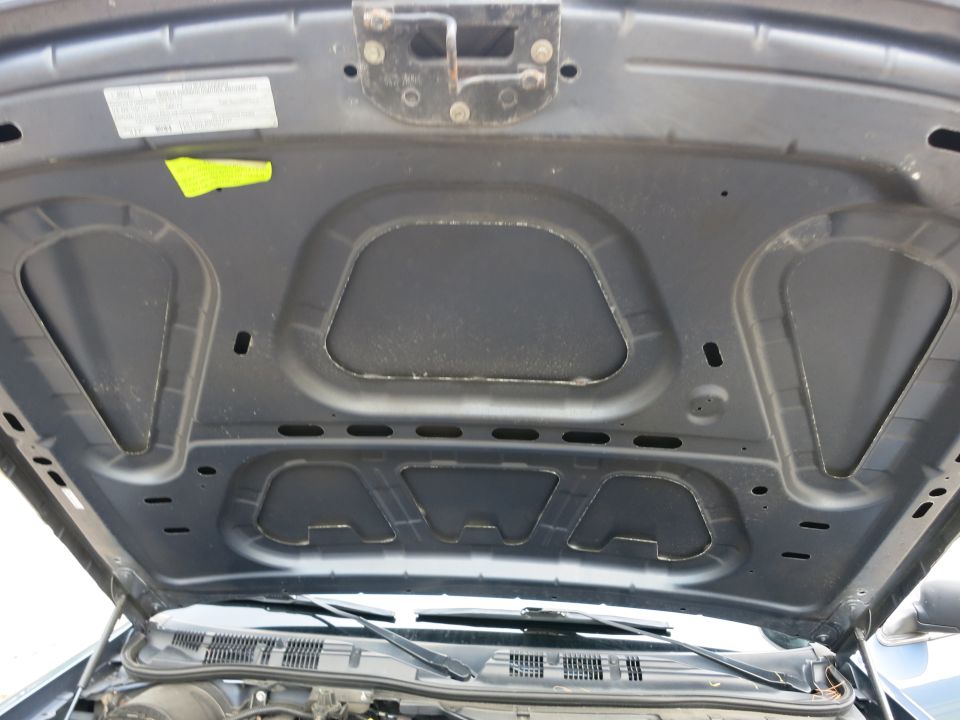 Underside of a car hood with insulation and latch mechanism visible