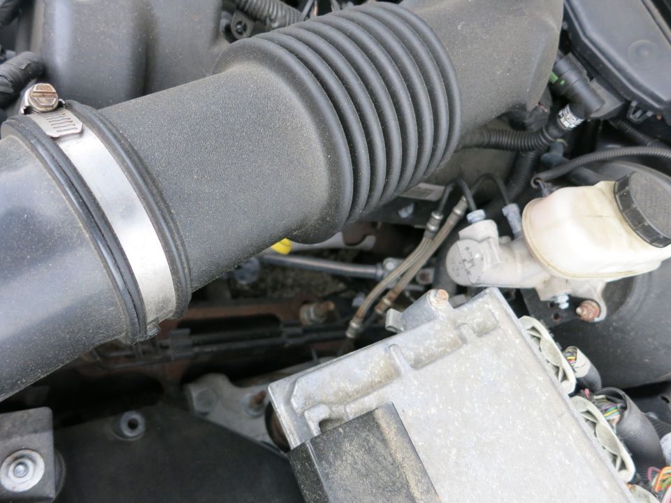 Close-up of engine parts including air intake hose, brake fluid reservoir, and electronic control unit