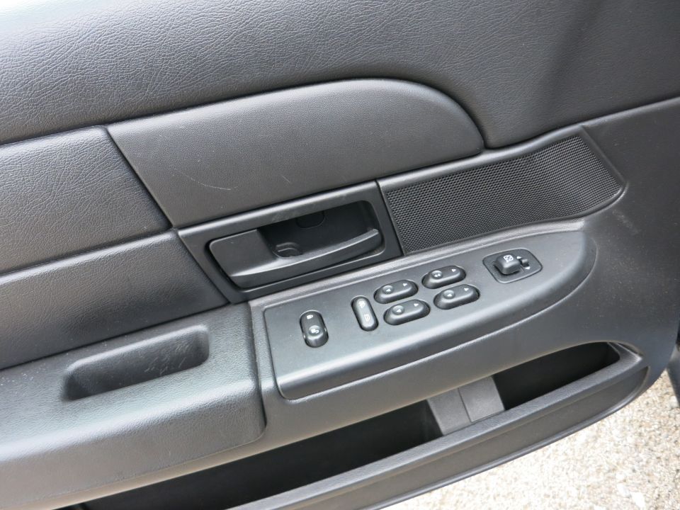 Black car door panel with power window controls and a door handle
