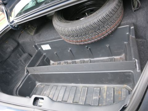 2001 Ford Crown Victoria - The spare tire is stored in the trunk of a car, above a plastic organizer.