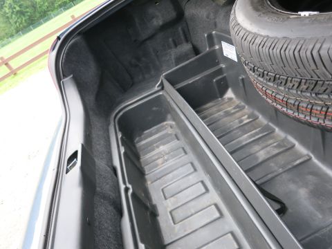 2001 Ford Crown Victoria - The trunk of a vehicle, showing the spare tire and integrated storage compartments.