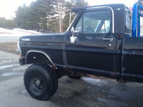 1970 Ford F-250 - This black 1970 Ford F-250 pickup truck is viewed from the front three-quarter angle, revealing its condition and modifications.