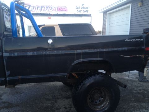 1970 Ford F-250 - This 1970 Ford F-250 Sport Custom pickup truck is seen from the side, a prominent blue roll bar in the bed.